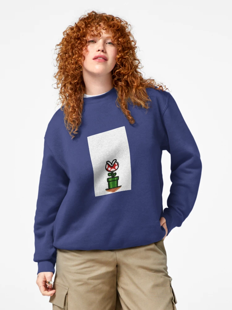 Femme qui porte un sweat bleu marine Super Mario avec le personnage de la plante Piranha rouge et vert