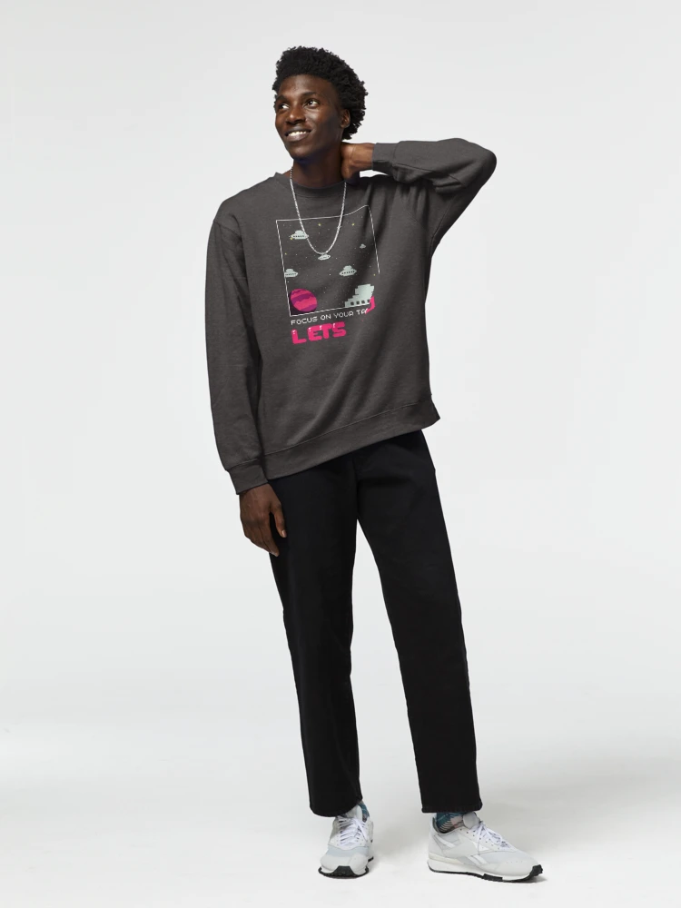 Homme qui porte un sweat gris foncé avec tout un univers pixels et écriture Let's Go