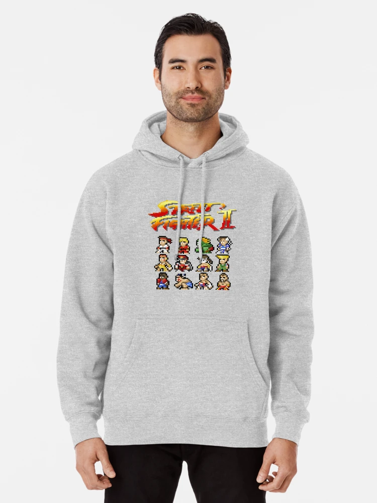 Homme qui porte un sweat gris clair Street Fighter avec tous les personnages pixelisés