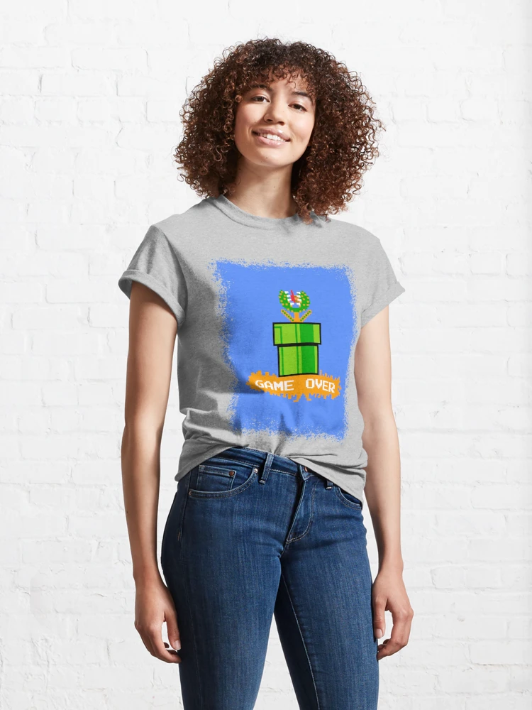 Femme qui porte un tee-shirt gris clair Super Mario avec le personnage de la plante Piranha bleu et verte